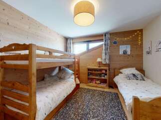 This charming ski chalet bedroom features a cozy bunk bed and a single bed, perfect for families or groups.