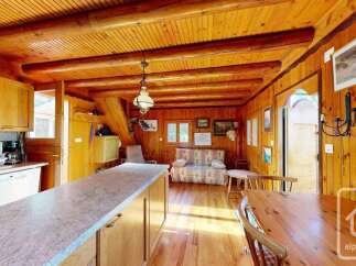 Experience rustic charm in this cozy log cabin kitchen and living area, featuring warm wooden interiors and exposed beams.