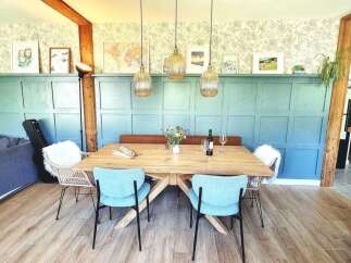 This dining room features a large wooden table with light blue chairs and a cozy bench seat.
