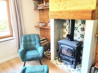 Cozy living room featuring a teal armchair and ottoman, perfect for relaxing by the wood-burning stove.