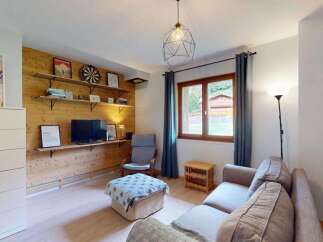 Cozy living room featuring a wooden accent wall with shelves displaying decor and a TV.