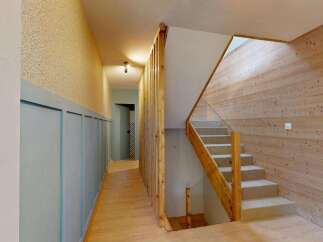 This modern home features a stunning staircase with a wooden railing and glass panels, leading to an upper level.