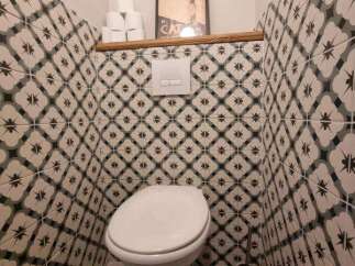 This modern bathroom features a stylish toilet with a concealed cistern, complemented by eye-catching patterned tiles on the walls.
