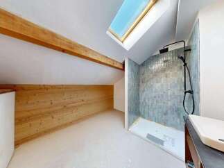 Discover this unique bathroom featuring a stylish shower with blue-green tiled walls and a modern black showerhead.