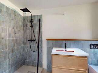 Experience modern comfort in this beautifully tiled bathroom featuring a sleek black shower system and a stylish vanity with ample storage.