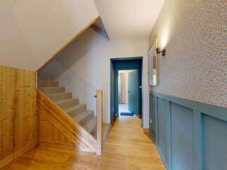 This modern home features a stunning staircase with glass balustrades and warm wooden accents, creating an inviting entryway.