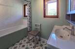 This charming bathroom features a classic white bathtub with a herringbone tile backsplash, complemented by a decorative patterned floor.