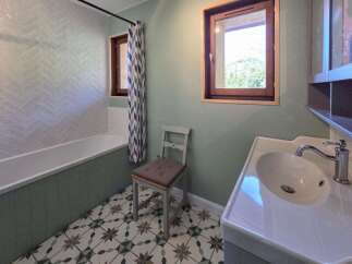 This charming bathroom features a classic white bathtub with a herringbone tile backsplash, complemented by a decorative patterned floor.
