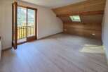 This spacious attic room features a beautiful wooden-paneled sloped ceiling with a skylight, offering natural light and a cozy ambiance.