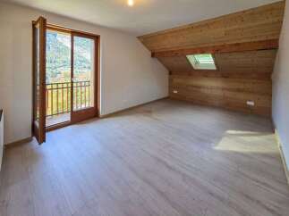 This spacious attic room features a beautiful wooden-paneled sloped ceiling with a skylight, offering natural light and a cozy ambiance.