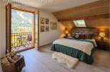 Experience the charm of this mountain retreat, featuring a cozy bedroom with a rustic wooden headboard and a plush knit blanket.