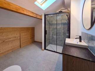 Experience modern comfort in this attic bathroom, featuring a sleek walk-in shower with stylish tiled walls and a contemporary vanity with a vessel sink.
