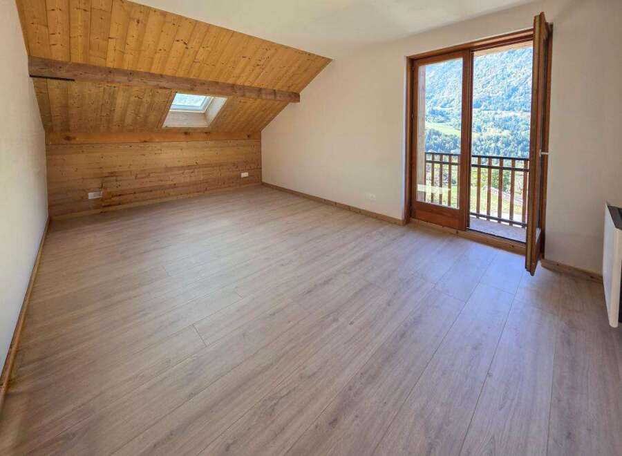 Experience breathtaking mountain views from this charming attic room, featuring a sloped wooden ceiling and a skylight that floods the space with natural light.