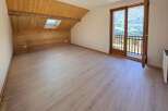 Experience breathtaking mountain views from this charming attic room, featuring a sloped wooden ceiling and a skylight that floods the space with natural light.