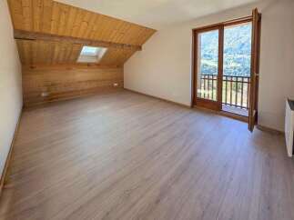 Experience breathtaking mountain views from this charming attic room, featuring a sloped wooden ceiling and a skylight that floods the space with natural light.