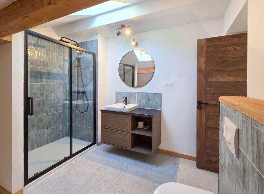 This modern bathroom features a sleek walk-in shower with grey tiled walls and a black frame.