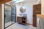 This modern bathroom features a sleek walk-in shower with grey tiled walls and a black frame.