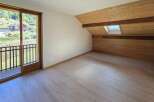Experience breathtaking mountain views from this charming attic bedroom, featuring a private balcony and a cozy, wood-paneled ceiling with a skylight.