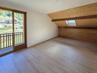 Experience breathtaking mountain views from this charming attic bedroom, featuring a private balcony and a cozy, wood-paneled ceiling with a skylight.