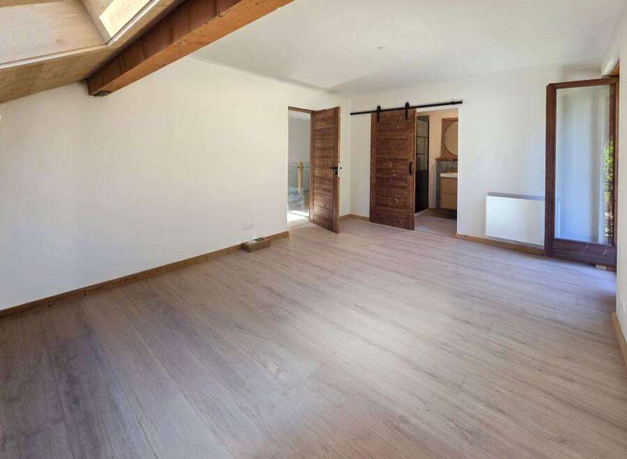 This spacious room features a modern, light wood-plank floor and crisp white walls, creating a bright and airy atmosphere.
