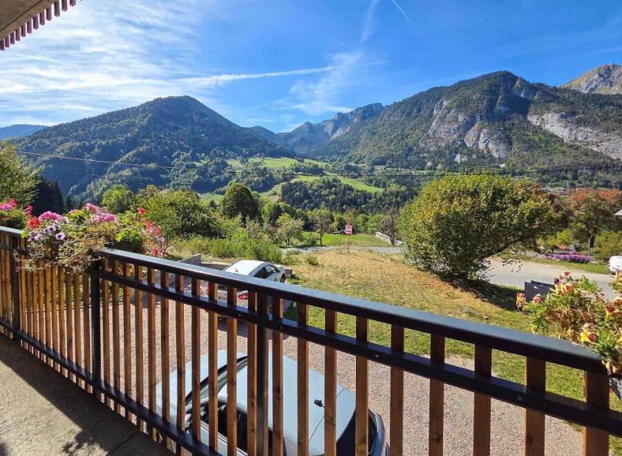 Enjoy breathtaking mountain views from this charming property's balcony, adorned with vibrant flowers.