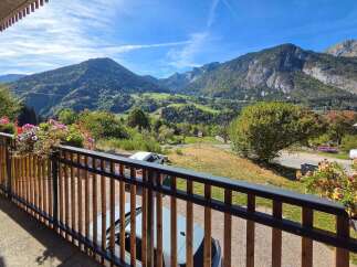 Enjoy breathtaking mountain views from this charming property's balcony, adorned with vibrant flowers.