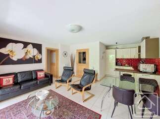 This spacious living area features a comfortable black leather sofa adorned with decorative pillows, complemented by two modern black leather armchairs.
