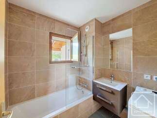 This modern bathroom features a spacious bathtub with a glass shower screen, perfect for relaxing after a long day.