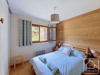 Experience cozy mountain living in this charming bedroom featuring a warm wooden accent wall and a comfortable bed with patterned bedding.