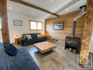 Experience cozy mountain living in this charming living room featuring a modern wood-burning stove and exposed wooden beams.