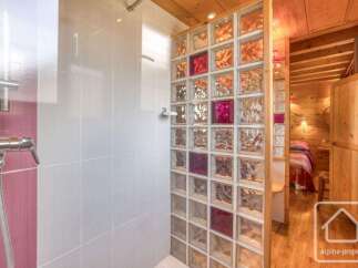 Experience a unique bathroom design featuring a stylish shower with white tiled walls and a striking glass block partition.