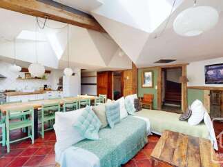 Discover this charming open-plan living space featuring a rustic kitchen with a gas range and ample counter space, perfect for culinary adventures.
