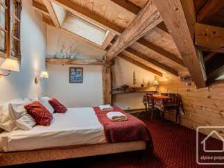 Experience cozy mountain living in this charming attic bedroom, featuring exposed wooden beams and a sloped ceiling.