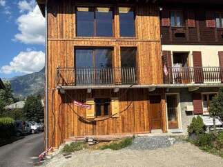 Discover this charming wooden house featuring a modern facade with large windows and a balcony, perfect for enjoying mountain views.