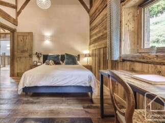 Experience rustic charm in this beautifully appointed bedroom, featuring exposed wooden beams and a cozy atmosphere.