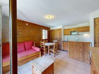 Experience cozy living in this charming studio apartment featuring a rustic wooden interior and a comfortable red sofa.