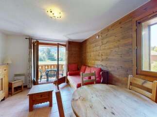 Experience cozy living in this charming mountain retreat, featuring a rustic wooden interior and a comfortable red sofa.