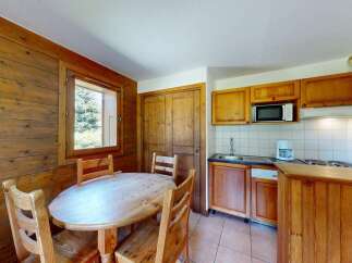 Experience cozy living in this charming kitchen and dining area, featuring warm wooden paneling and a rustic wooden table with chairs.