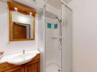 This charming bathroom features a spacious vanity with a white sink and ample wooden cabinetry, perfect for storage.