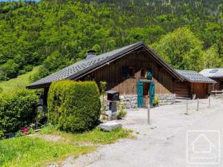 Nestled against a lush green mountainside, this charming wooden chalet offers a rustic alpine retreat.
