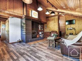 Experience rustic charm in this cozy living room featuring a grand stone fireplace and warm wood paneling throughout.