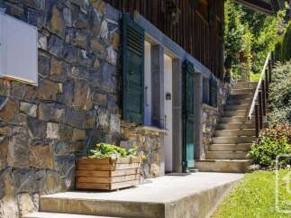 Discover this charming property featuring a rustic stone facade complemented by traditional green shutters.