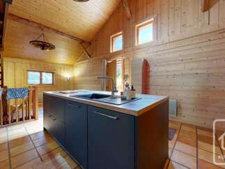 Experience the charm of this rustic kitchen, featuring a sleek dark island with a modern faucet and sink, perfect for meal preparation.