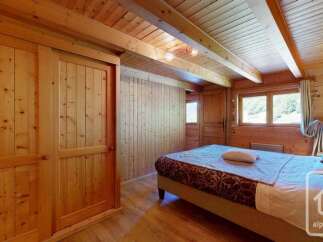 Experience cozy mountain living in this charming wooden bedroom, featuring a spacious built-in wardrobe and a comfortable bed.
