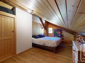Discover this charming attic bedroom featuring a cozy bed with blue pillows, perfect for a relaxing retreat.
