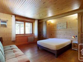 Experience rustic charm in this cozy bedroom featuring warm wood paneling throughout and a comfortable sofa for relaxation.