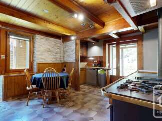 Experience rustic charm in this cozy kitchen featuring warm wooden beams and paneling throughout.