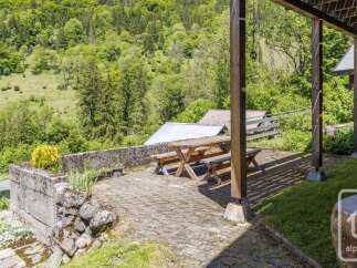 Enjoy the serene mountain views from this charming property, featuring a covered patio with a picnic table perfect for outdoor dining.