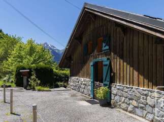 Experience rustic charm in this wooden chalet, nestled amidst lush greenery with a stunning mountain backdrop.