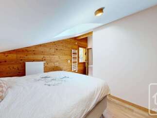 Experience cozy living in this charming bedroom featuring warm wooden paneling and a comfortable bed.